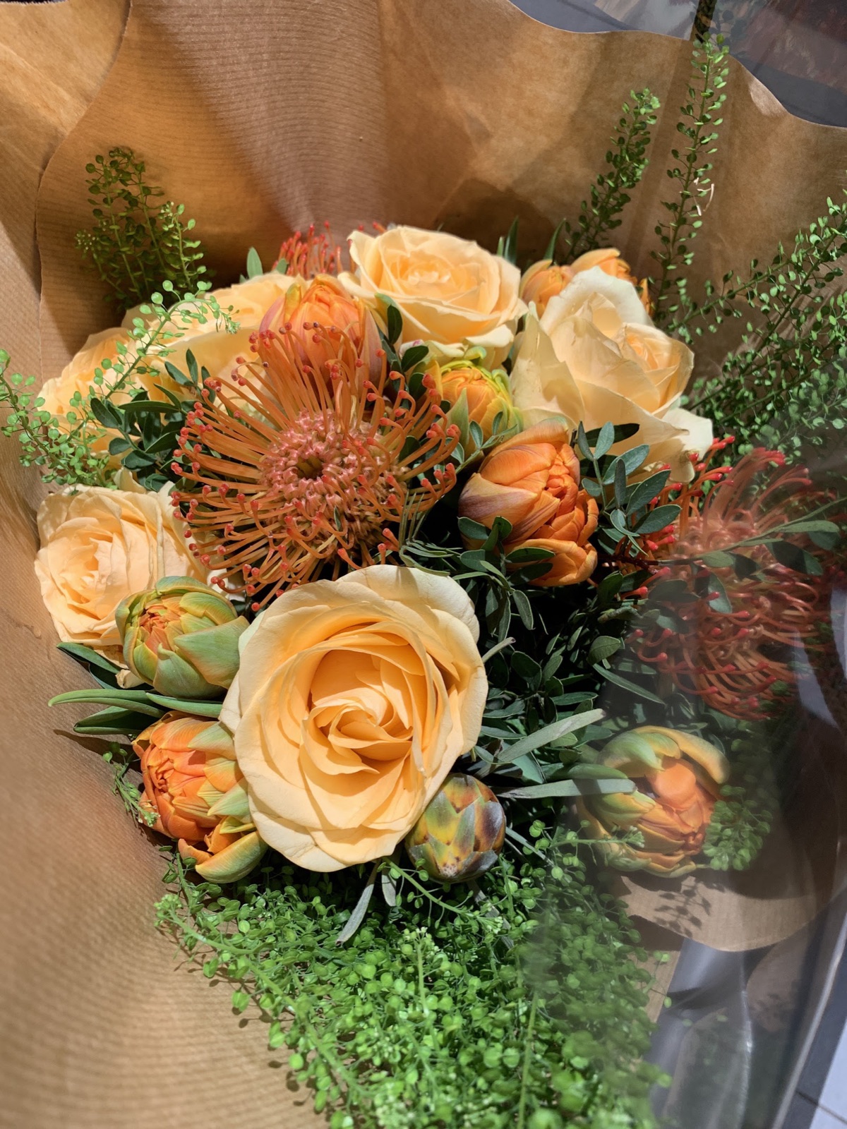 Mixed bouquet in orange wrap with a decorative butterfly